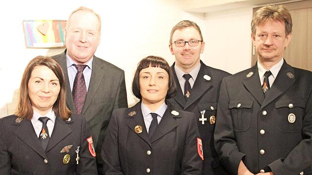 Antje Wolkenstein-Puttins (Mitte) ist die neue Vorsitzende der Lopper Feuerwehr und damit Nachfolgerin von Andreas Schilde (rechts). Simone Meisel (links) wurde f&uuml;r 25 Jahre in der Wehr geehrt. Dahinter stehen stellvertretender B&uuml;rgermeister Klaus Amschler und Gerald Sch&ouml;ps (Kommandant). Foto: Katharina M&uuml;ller-Sanke