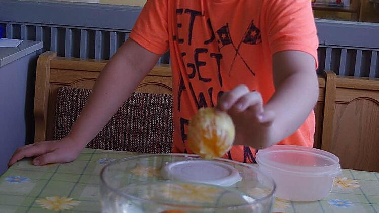 Jakob zeigt den Versuch mit den schwimmenden und sinkenden Orangen.  Foto: Heike Schülein