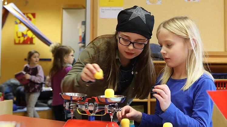 Louisa und Jule (unten links) lernen an der Experimentierstation mit unterschiedlich schweren Überraschungsei-Büchsen, wie ein Computer Daten sortiert. Foto: Barbara Herbst