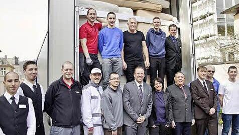 Ein Dutzend starker Männer packte am Donnerstag die ersten zwei Lastwagen mit Matratzen, Möbeln und Porzellan voll; nach der Arbeit präsentierten sie sich mit (vordere Reihe) Hoteldirektor Michael Hecht (6. v.l.), Hotelgeschäftsführerin Andrea Hergenröther, Hilfsorganisator und Kirchenvorstand Wulf Carstensen aus Essen und der stellvertretende Hotelgeschäftsführer Thomas Lehmann. Foto: Sigismund von Dobschütz