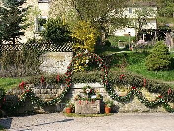 Der Schützenbrunnen am Ortseingang von Egloffstein wird mit Pensala, Papierrosen, Eier und Girlanden geschmückt. Fotos: Löwisch