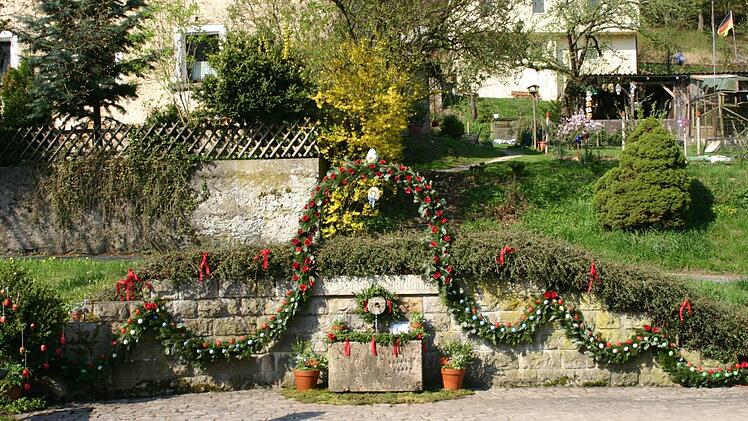 Der Schützenbrunnen am Ortseingang von Egloffstein wird mit Pensala, Papierrosen, Eier und Girlanden geschmückt. Fotos: Löwisch