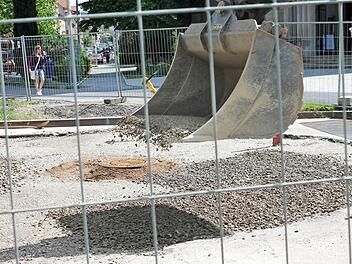 Die Baugrube vor der Kirche ist gefüllt und wird provisorisch asphaltiert. Auf dem Bild verteilt ein Bagger eine Schotterschicht.  Foto: Benedikt Borst