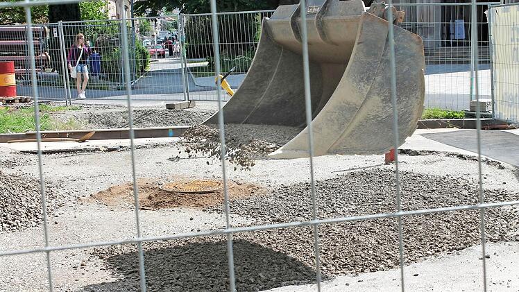 Die Baugrube vor der Kirche ist gefüllt und wird provisorisch asphaltiert. Auf dem Bild verteilt ein Bagger eine Schotterschicht.  Foto: Benedikt Borst