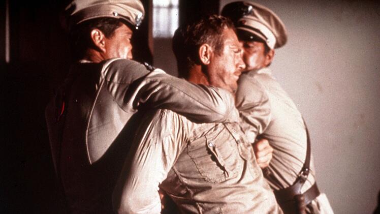 Der aufs&auml;ssige Str&auml;fling Henri Charri&egrave;re alias Papillon (Steve McQueen) wird von W&auml;rtern niedergerungen.
