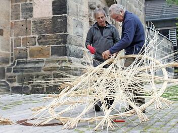Carlos Fontales (links) und Joan Farré Oliver aus Spanien haben schon mehrfach bei flechterischen Großprojekten zusammengearbeitet. Nun tun sie es in Lichtenfels. Unser Bild zeigt sie am Montag bei den Anfängen ihrer Arbeit vor der Stadtpfarrkirche. Foto: R. Popp