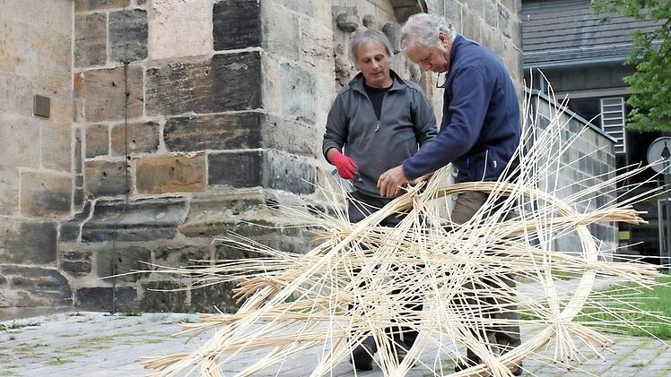Carlos Fontales (links) und Joan Farré Oliver aus Spanien haben schon mehrfach bei flechterischen Großprojekten zusammengearbeitet. Nun tun sie es in Lichtenfels. Unser Bild zeigt sie am Montag bei den Anfängen ihrer Arbeit vor der Stadtpfarrkirche. Foto: R. Popp