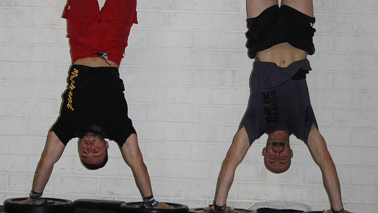 Sieben Minuten lang dauert eine Runde - und die Teilnehmer müssen immer abwechseln Handstand-Push-ups turnen und Gewichtheben. Erst zwei Handstand-Push-ups, zwei Mal Gewichtstemmen, dann vier Mal, dann sechs Wiederholungen. Die meisten Punkte bekommt der, der die "Workouts" perfekt durchführt und die meisten Wiederholungen schafft. Foto: Sonja Adam