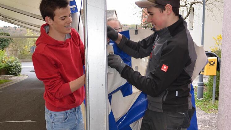 Tim (links) und Erik helfen beim Zeltaufbau in Katzenbach mit. Hier bringen sie eine Plane am Gestänge an.  Foto: Kathrin Kupka-Hahn