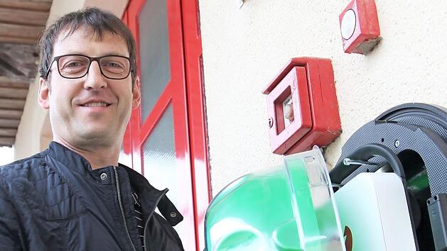 Am Feuerwehrgerätehaus in Jesserndorf hängt ein Defibrillator. Der Vorsitzende Manfred Bühler nimmt die grüne Schutzhaube ab, unter der das Gerät ist.  Foto: BRK