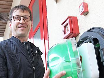 Am Feuerwehrgerätehaus in Jesserndorf hängt ein Defibrillator. Der Vorsitzende Manfred Bühler nimmt die grüne Schutzhaube ab, unter der das Gerät ist.  Foto: BRK