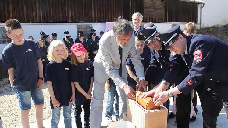Bürgermeister Martin Rauscher, Kommandant Andreas Hackl und sein Stellvertreter Michael Stüllein legen die Zeitkapsel in den Grundstein. Michael Stelzner