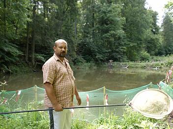 Verzweifelt steht Alexander Gerber an seiner Teichanlage und holt tote Jungfische aus dem Wasser.  Fotos: Sabine Weinbeer