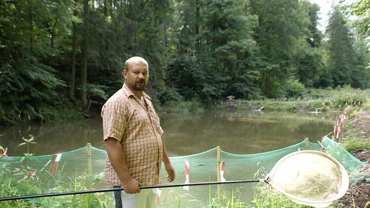 Verzweifelt steht Alexander Gerber an seiner Teichanlage und holt tote Jungfische aus dem Wasser.  Fotos: Sabine Weinbeer
