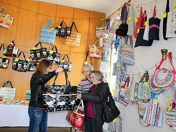 Bettina Eberhardt (links) freut sich über die gerade erstandene originelle Plastiktasche aus zusammengenähten ehemaligen Kaffeetüten. Wie ihre Mutter Hildegard (rechts) trägt die junge Frau aus Gleismuthhausen immer eine Einkaufstasche bei sich, um in Läden nicht auf Kunststofftragetaschen angewiesen zu sein. Christine Weschenfelder (hinten) und ihre Mitstreiterinnen von der Gemünner Lichtstube haben die Taschen angefertigt. Foto: Bettina Knauth