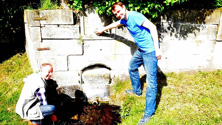 In Ditterswind steht eine beachtenswerte Brunnenanlage, die saniert werden soll. Hier informieren sich Zweiter Bürgermeister Harald Deringer (links) und Michael Rahn (rechts) von der Bauabteilung der Gemeinde über den "Wilhelmsbrunnen", der noch Wasser führt. Foto: Schmidt