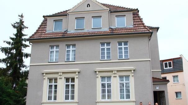 Howhannes Karapetian und sein Bruder Samwel nehmen vor ihrem Haus in der Victoriastraße die Plakette aus Eidts Händen erfreut entgegen. Foto: Katja Nauer
