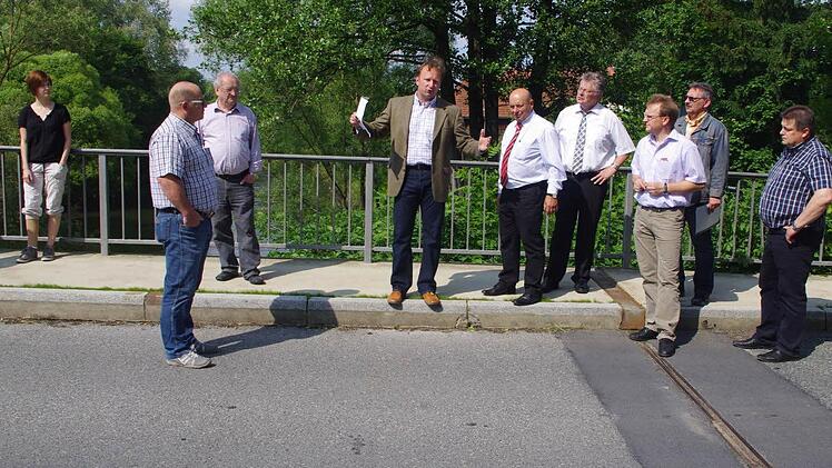 Markus Albrecht informiert auf der Rodachbrücke in Oberlangenstadt über notwendige Instandsetzungsmaßnahmen. Auf dem Beton ist die beschädigte Übergangs-Konstruktion (rechts) zu erkennen.