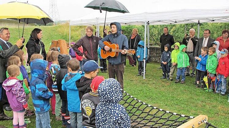 Regenschirme bestimmten die Szene, als Kindergartenkinder den neuen Hallstadter Wasserspielplatz feierten. Foto: Kerstin Bönisch