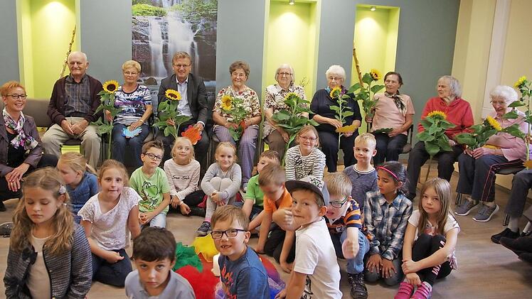 Die Schüler der Klasse 1 a der Grundschule Stockheim sind Freunde und Partner der Tagespflege Baierlein und bringen mit ihrem Besuch nicht nur Geschichten, Gedichte und Gesänge, sondern haben auch Sonnenblumen zur Freude für die Senioren dabei. Foto: K.- H. Hofmann