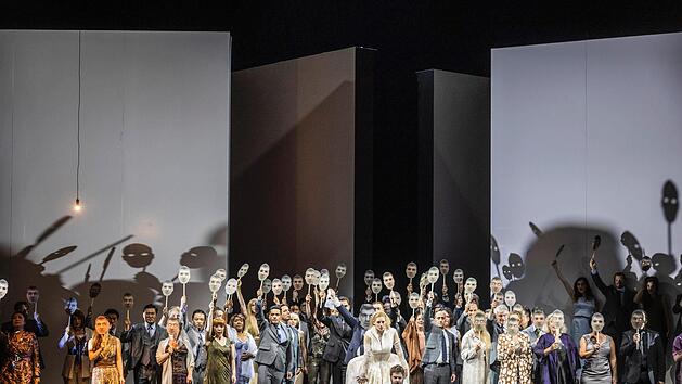 Die Hochzeitsszene offenbart, wie brachial K&ouml;nig Philipp II. (etwas verdeckt, mit der gr&ouml;&szlig;ten Maske: Nikolai Karnolsky) die Jungfr&auml;ulichkeit seiner Braut Elisabeth (in wei&szlig;er Robe: Emily Newton) pr&uuml;ft, die eigentlich seinem Sohn Don Carlos (kniend: Tadeusz Szlenkier) versprochen war.  Foto: Ludwig Olah