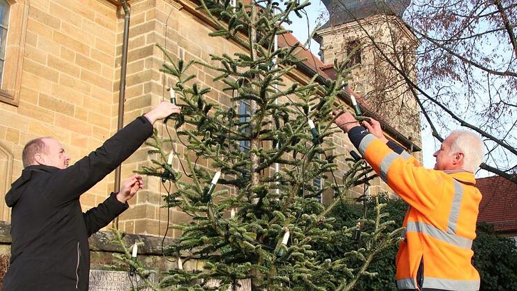 Zapfendorf hat seinen Christbaum wieder, wenn auch eine kleinere Version: Es sind die Reste der umgesägten Tanne vor der Kirche. Bernd Eichhorn (links) und Georg Wisocki bringen die Lichter an.  Foto: Sebastian Schanz