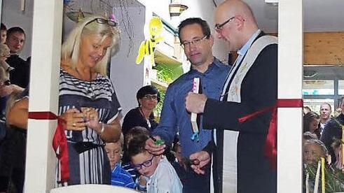 Mit dem Durchschneiden des Bands eröffnen (von links) Bürgermeisterin Susanne Grebner, Architekt Kersten Schöttner und Pfarrer Sven Raube die neue Krippe. Foto: Heike Schülein