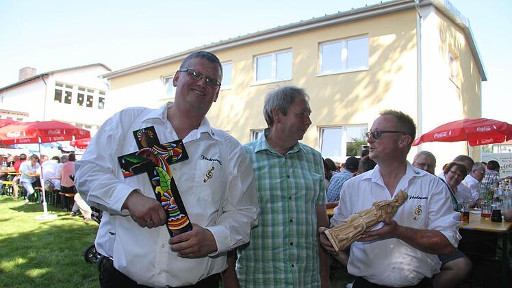 Holger Pohl nimmt von den Diakonen Malte Hahn und Wolfgang Fehn ein Kreuz in Empfang. Es wird einen Ehrenplatz im Probenheim bekommen. Roland Ringlstetter hat eine Cäcilia geschnitzt - überreicht sie Michael Scheler