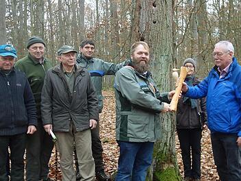 Das Ehrungspräsent, eine Holzskulptur, überreichte Christoph Hübner an Dietmar Westhäuser (beide Bildmitte) stellvertretend für alle am Förderprogramm Teilnehmenden als eine Anerkennung für die Nichtnutzung einzelner Bäume, trotz sachgemäßer Holznutzung.  Foto: Doris Weidner