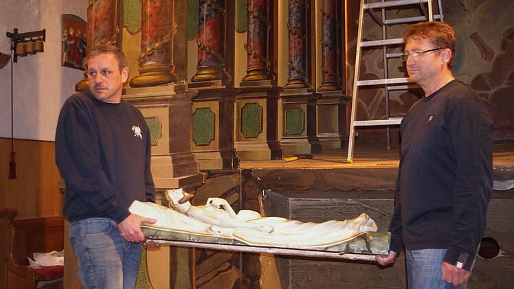 Roland Reißig und Daniel Kaim (von links) tragen den "Leichnam" Christi, der im "Heiligen Grab" aufgebahrt wird.