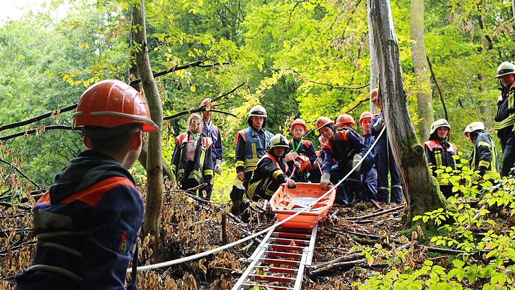 Mit Unterst&uuml;tzung durch erfahrene Feuerwehrleute mussten die Jugendlichen einen verletzten Waldarbeiter mit Hilfe einer Schleifkorbtrage aus unwegsamem Gel&auml;nde retten.  Foto: Luca Berger