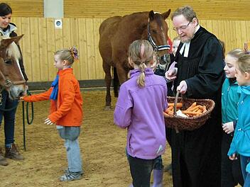 Pfarrer Ulrich Rauh verteilt Segnungsmöhren, mit denen die Kinder wiederum die Pferde erfreuen.  Fotos: Dieter Grams