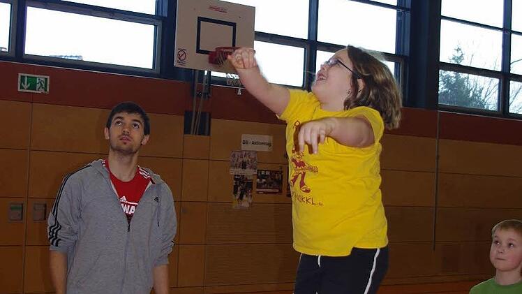 Unter Anleitung von Brose-Baskets-Jugendtrainer Florian Tilch übt Anna Feldtmann den Korbwurf. Mit im Bild ist Max Breitkreuz (rechts).