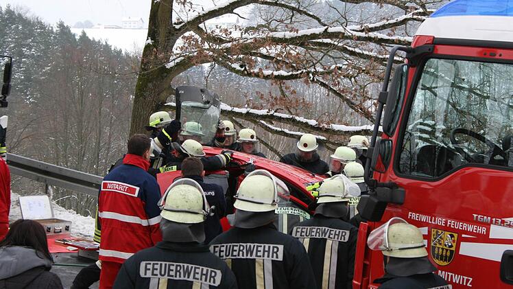 Feuerwehrleute heben das Dach des Kleinwagens an.