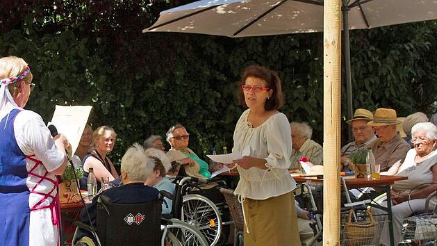 : Luther (braun-wei&szlig;es Gewand) und Herr Tetzel (pinkes Gewand) streiten um die Ablassbriefe (dargestellt durch Mitarbeiterinnen)