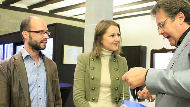 Richard Loibl, Direktor des Hauses der Bayerischen Geschichte, (rechts) &uuml;berreicht sein Geschenk an die 150.000. Besucher, Mathias und Julia Kraus. Foto: Dominic Buckreus