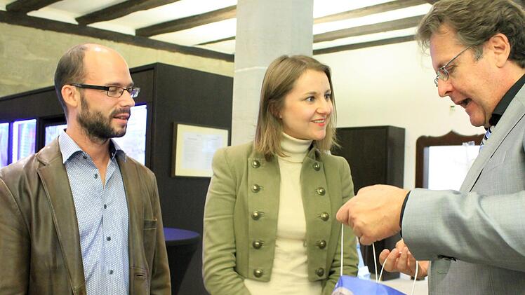 Richard Loibl, Direktor des Hauses der Bayerischen Geschichte, (rechts) überreicht sein Geschenk an die 150.000. Besucher, Mathias und Julia Kraus. Foto: Dominic Buckreus