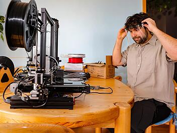 Steffen Burger mit seinem 3D-Drucker, mit dem er seit einer Woche ehrenamtlich Schutzvisiere produziert. Er koordiniert das fränkische Hilfsangebot. Foto: Matthias Hoch