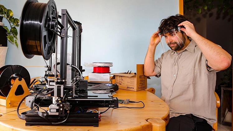Steffen Burger mit seinem 3D-Drucker, mit dem er seit einer Woche ehrenamtlich Schutzvisiere produziert. Er koordiniert das fränkische Hilfsangebot. Foto: Matthias Hoch