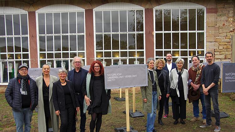 Vor der Orangerie stehen die Kunstschaffenden mit Schrifttafeln  ( von links) Alexander Ruppert, Romana Kochanowski, Eva Feichtinger, Konrad Winter, Katja Then, Ulrike Heim, Heide Lauter, Stephan Mundi, Silvia Pfister-Stanjek, Carlo Cantoni und Re...