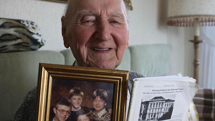 Rudolf Demel zeigt lächelnd ein über 20 Jahre altes Bild seiner Tochter Edda, des Schwiegersohns Ernst und der Enkel Matthias und Stefan. Daneben hält er  ein Schwarzweiß-Foto von Demels einstiger Schule in Wagstadt - kein nüchterner Zweck-, sondern ein stolzer Prachtbau.  Foto: Diana Fuchs
