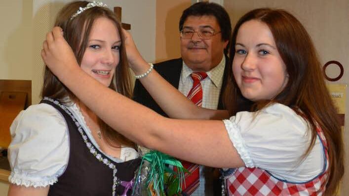 Die bisherige Weinkönigin Laura Fritsch (rechts) setzt ihrer Nachfolgerin Theresa Tumbach die Krone auf. Im Hintergrund Wolfgang Förtsch, Vorsitzender der Aktionsgemeinschaft Markt Pressig. Foto: Karl-Heinz Hofmann