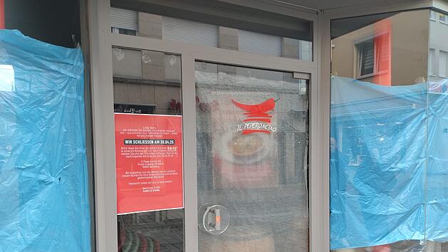 Geschäftsfassade mit einem Schild des "Il Peperoncino". Im Schaufenster hängt eine rote Abschiedsbotschaft, umgeben von blauer Abdeckung. Das Restaurant schließt am 30.04.2025.