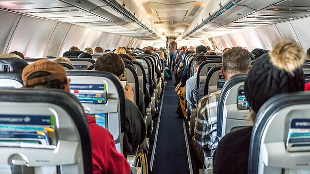 Passengers seated inside of a commercial passenger airplane. Tra Verstellbare Sitzlehnen, Sitzlehne Flugzeug, Kostenpflichtige Sitzlehnen, Flugzeug Komfort, Premium-Sitze Flugzeug, Economy-Class Komfort, Neue Sitzkategorien Flugzeug, Extended Comfort Section, Standard-Economy Sitze, Beinfreiheit Flugzeug, Kabinenaufteilung Airlines, Fluggesellschaft Komfortmodell, Zus&auml;tzliche Sitzreihen Flugzeug, Ergonomische Sitzpolsterung, Aufpreis f&uuml;r Sitzkomfort.