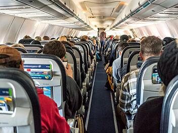 Passengers seated inside of a commercial passenger airplane. Tra Verstellbare Sitzlehnen, Sitzlehne Flugzeug, Kostenpflichtige Sitzlehnen, Flugzeug Komfort, Premium-Sitze Flugzeug, Economy-Class Komfort, Neue Sitzkategorien Flugzeug, Extended Comfort Section, Standard-Economy Sitze, Beinfreiheit Flugzeug, Kabinenaufteilung Airlines, Fluggesellschaft Komfortmodell, Zus&auml;tzliche Sitzreihen Flugzeug, Ergonomische Sitzpolsterung, Aufpreis f&uuml;r Sitzkomfort.