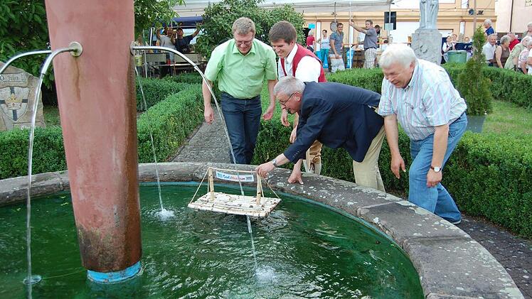 Das Floß geht zu Wasser. Bürgermeister Gotthard Schlereth gibt mit einem Schubs noch die Richtung an. V.l. 2.Bürgermeister Jürgen Kolb, Vorsitzender Markus Emmert, Bürgermeister Gotthard Schlereth und von der Musikakademie Helmut Lapp Foto: Günther Straub