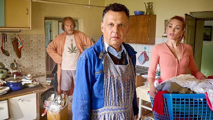 Papa Eberhofer (Eisi Gulp, links), Leopold (Gerhard Wittmann) und Susi (Lisa Maria Potthoff) sind überfordert mit dem Haushalt der Familie. Denn Oma hat die Schürze und den Kochlöffel niedergelegt.