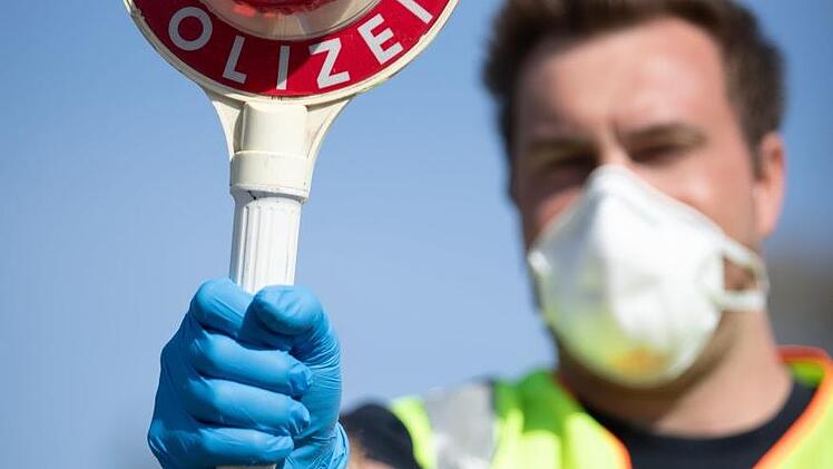 Ein Beamter, der bei einer Verkehrskontrolle Schutzausrüstung trägt.  Symbolbild: Friso Gentsch/dpa