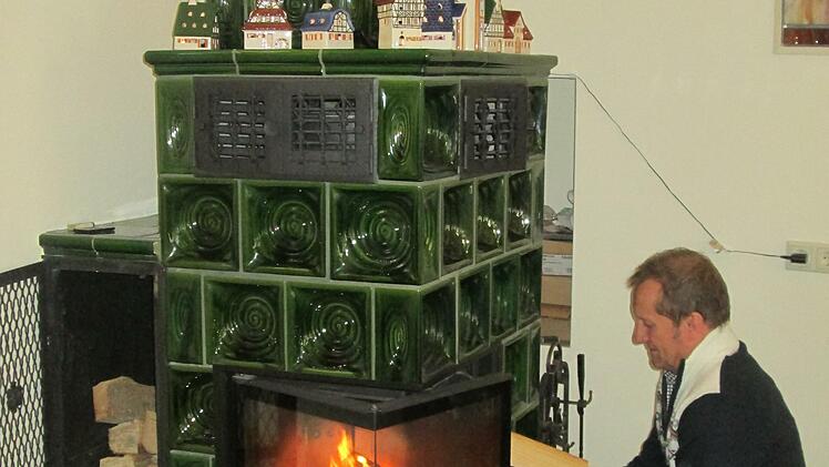 Willi Volkert heizt den Kachelofen an, den er selbst in Aschaffenburg ab- und in der Saalestadt aufgebaut hat. Foto: Winfried Ehling