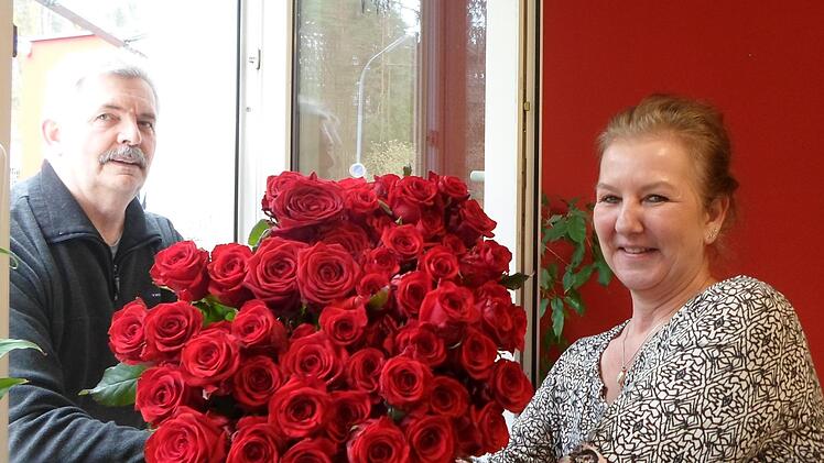 Durchs Fenster gereicht: Sabine Preisendörfer vom Willy-Brandt-Haus der Awo freut sich über 100 Rosen für Bewohner und Mitarbeiter. Jürgen Hurrlein hat sie gespendet. Foto: Elke Hohmann